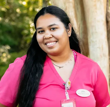 Ariana, a member of the checkout staff at Coastal Carolina Aesthetics, poses outside smiling wearing pink scrubs.