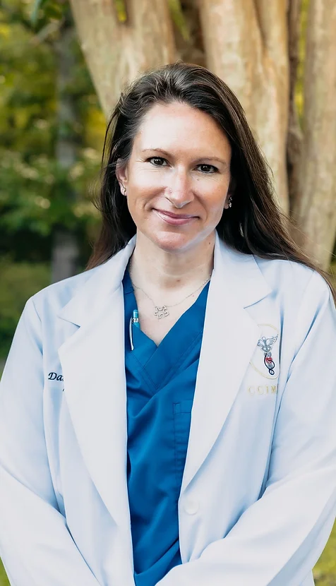 Daina Barber, physician's assistant at Coastal Carolina Aesthetics, poses outside wearing blue scrubs and a white lab coat over it.