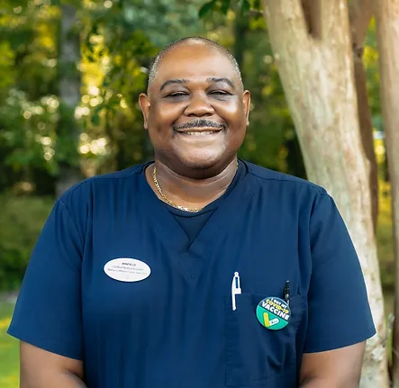 Winfield, medical assistant to Daina Barber at Coastal Carolina Aesthetics, poses outside smiling wearing navy blue scrubs.